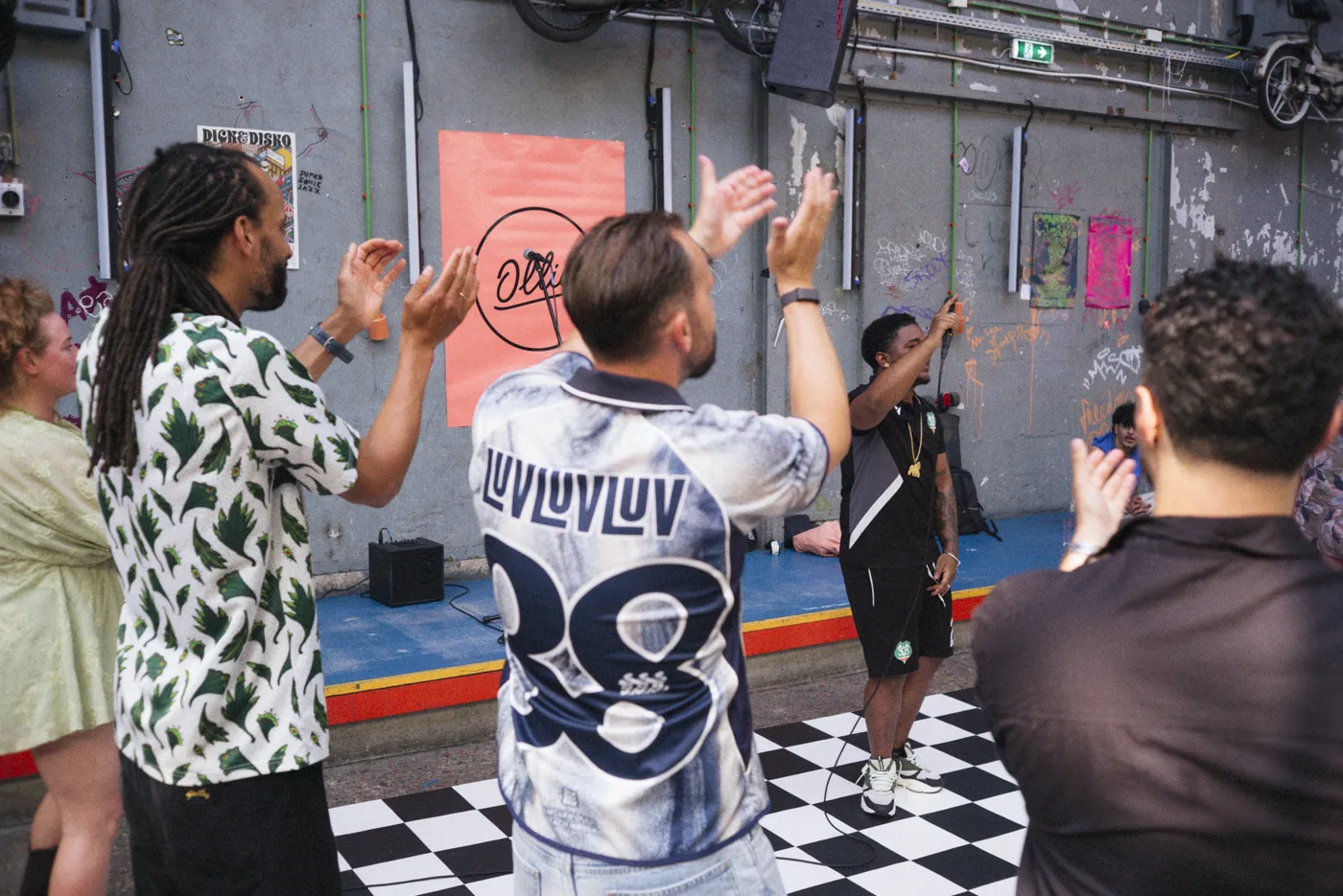 Benjamin en Chudi applaudisseren voor een rapper tijdens een optreden op het 10-jarig jubileum van Ollie
